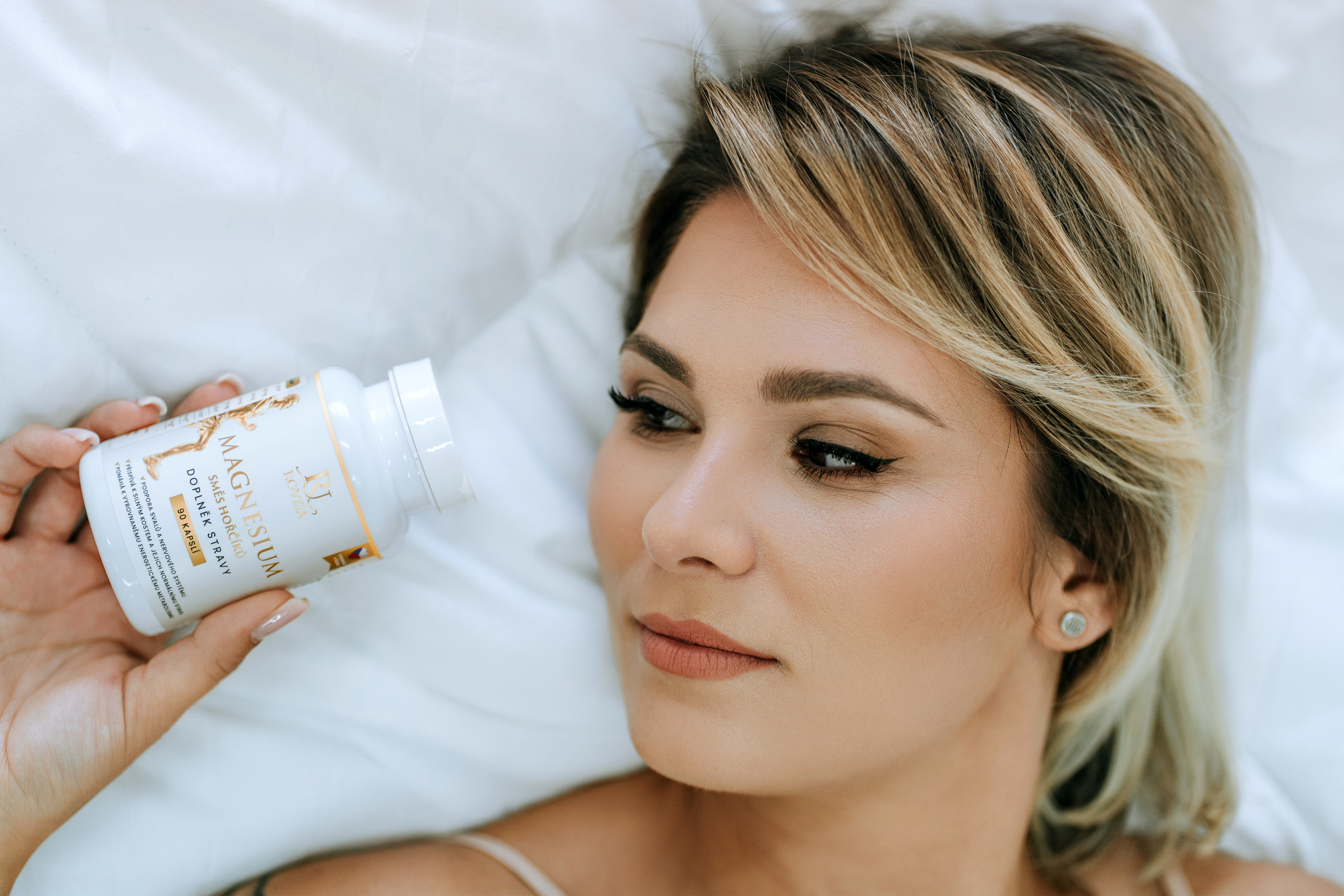 Žena ležící v posteli s doplňkem stravy Roveja Magnesium pro kvalitní spánek